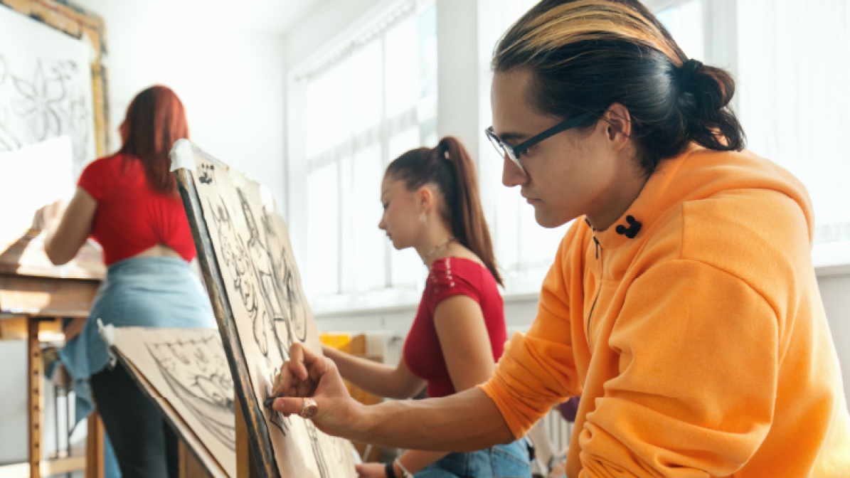 A photo of a group of art students sitting painting in a classroom