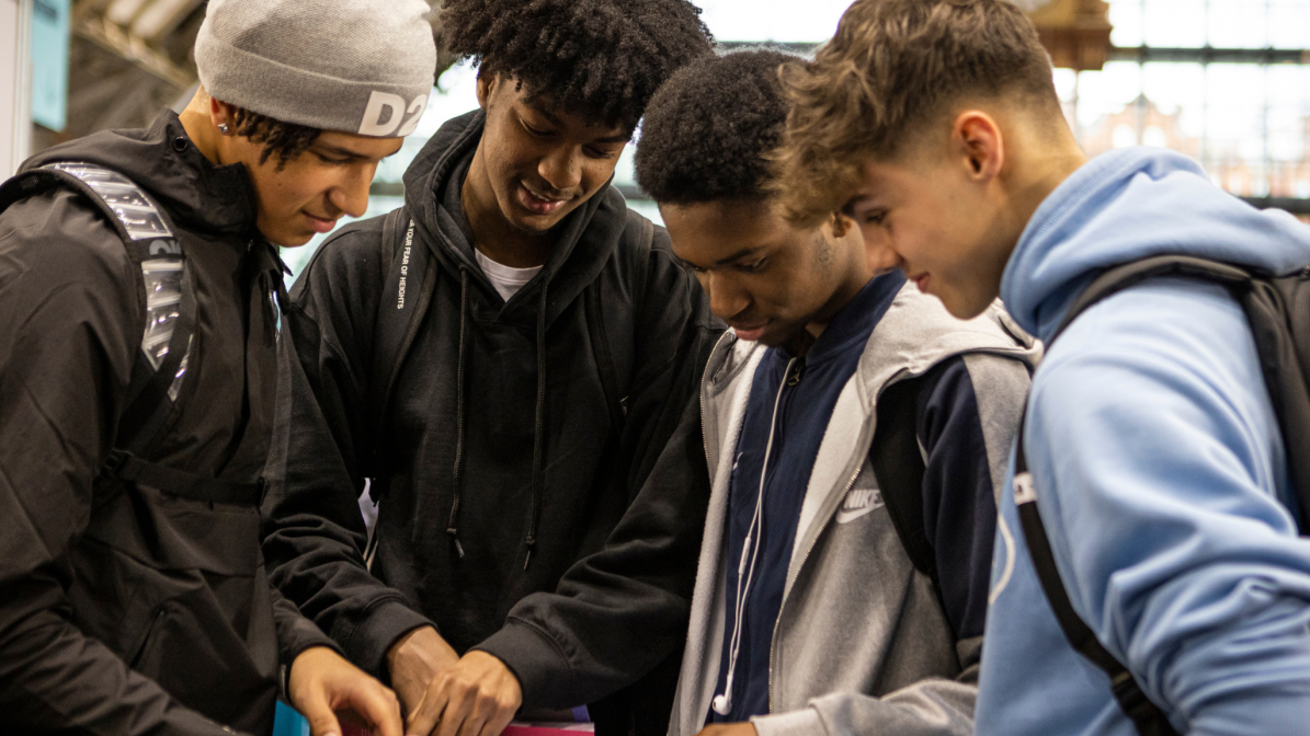 A group of students looking at an event guide at the UCAS Discovery Manchester event