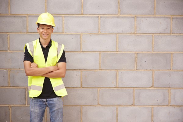 Building and construction apprentice standing against wall