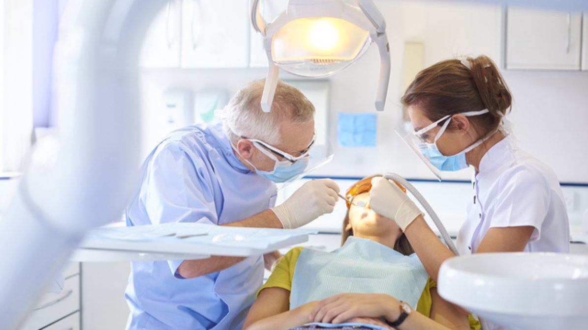 Endodontist and dental nurse carrying out dental work on patient